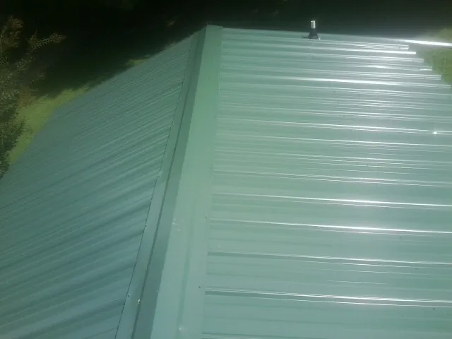 New green metal panels meeting at the ridge of a roof — Flat Roof Repair work by our crew in Ashley