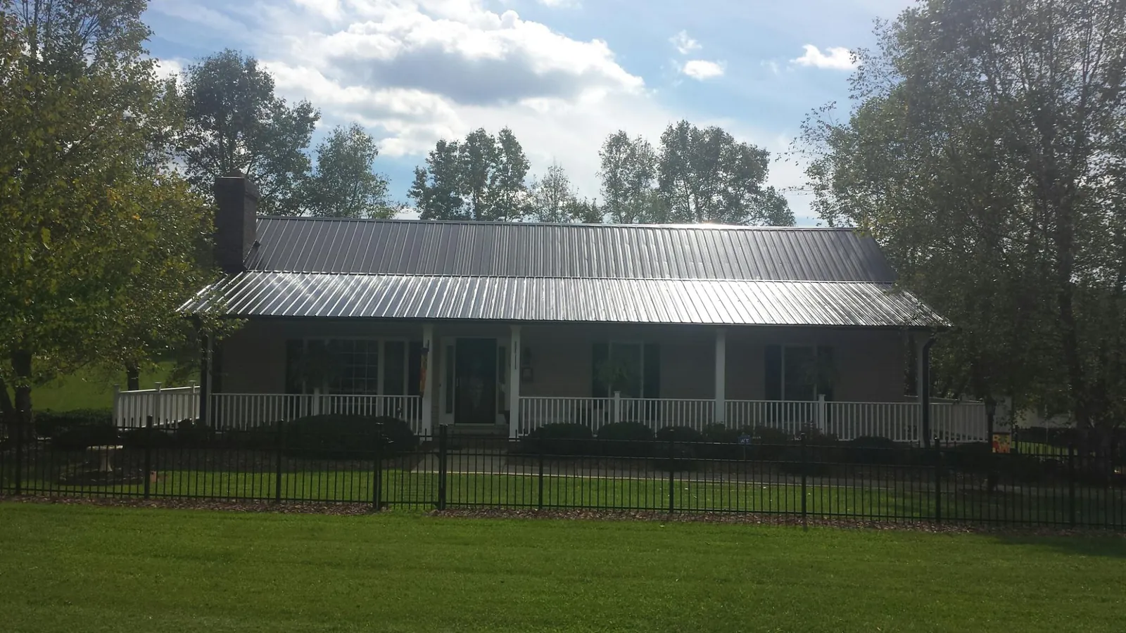 Gray metal roof on a brick ranch with a full width front porch — Gutter Guard Installation work by our crew in Ashley