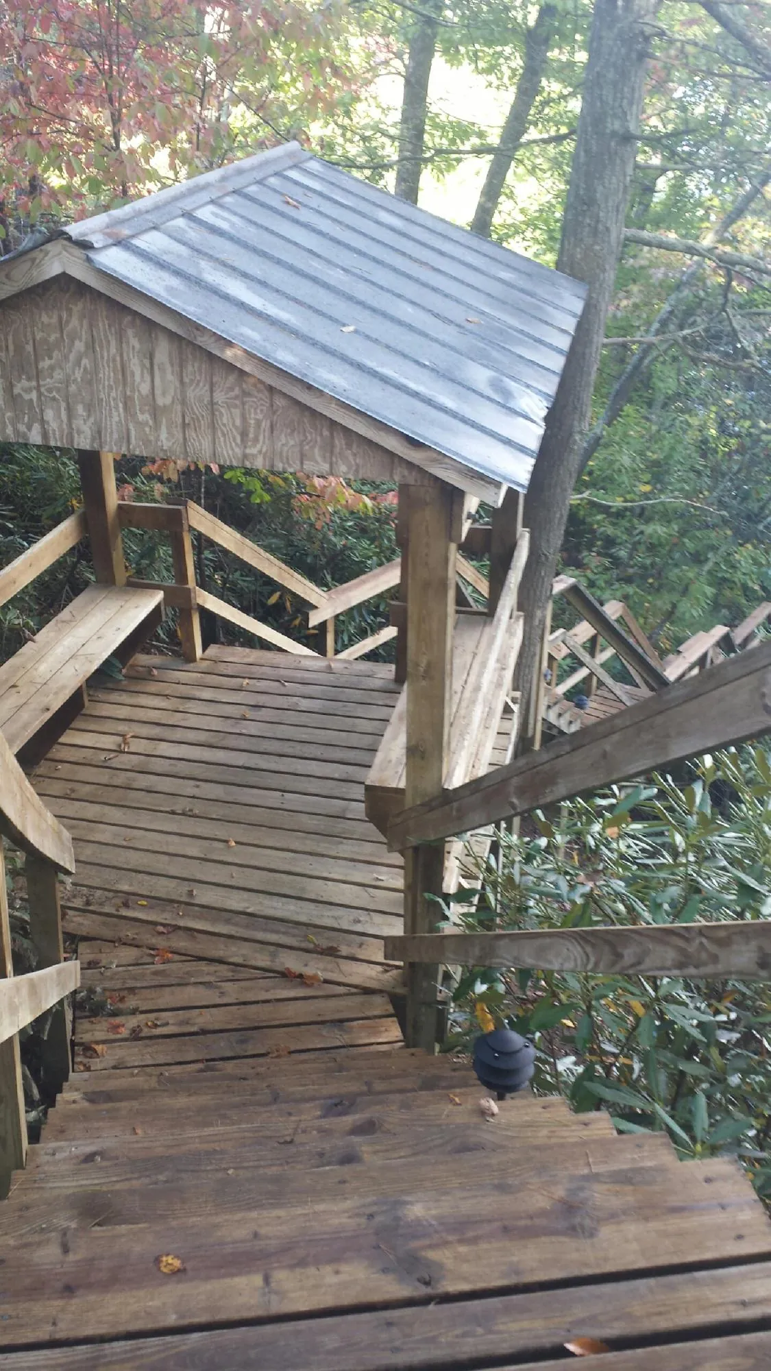 Metal roofed shelter over wooden steps on a wooded walkway — Skylight Repair & Installation work by our crew in Ashley