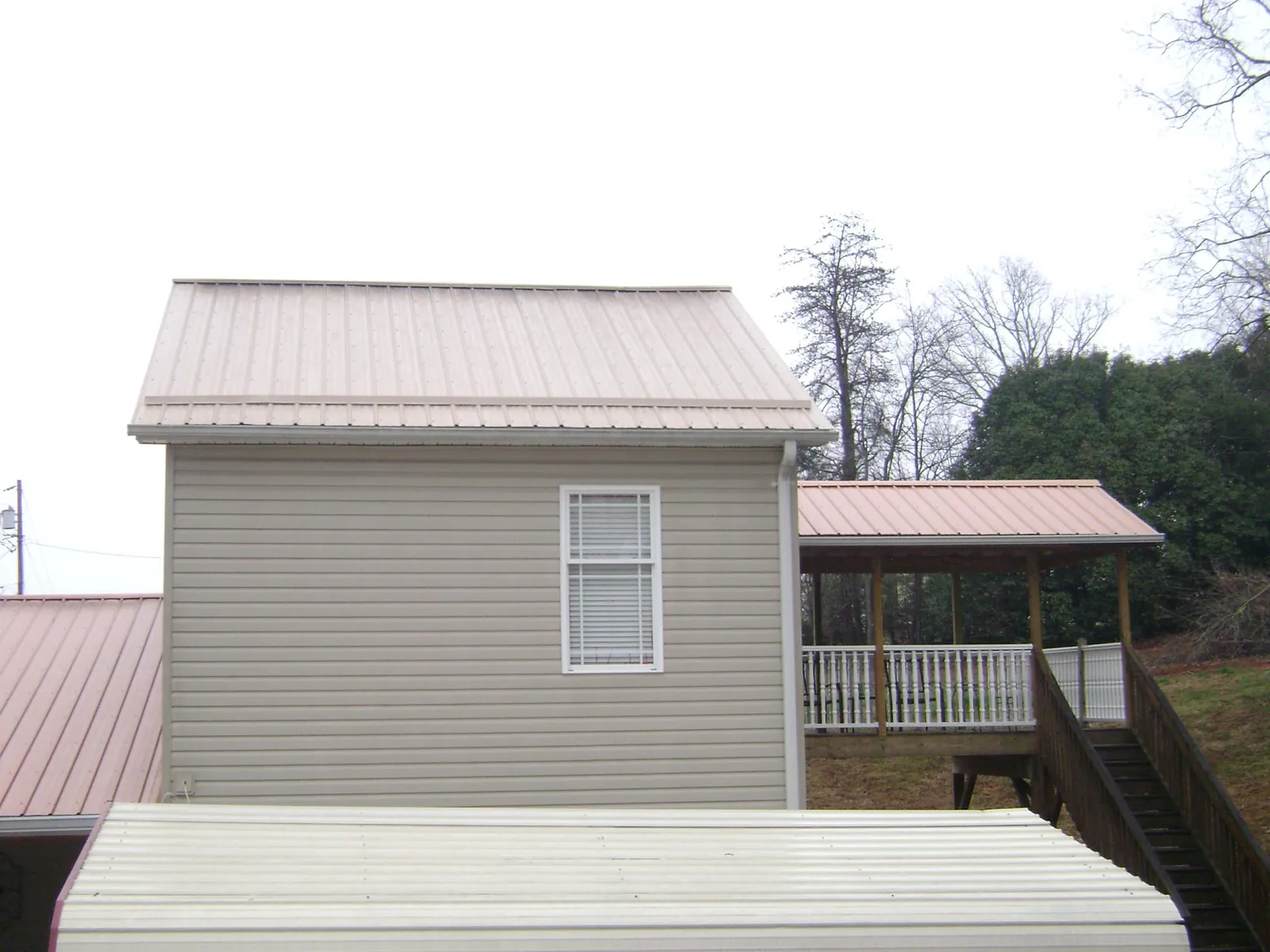 Tan metal roofs on a two story addition and attached porch, from a Roof Replacement job in Ashley
