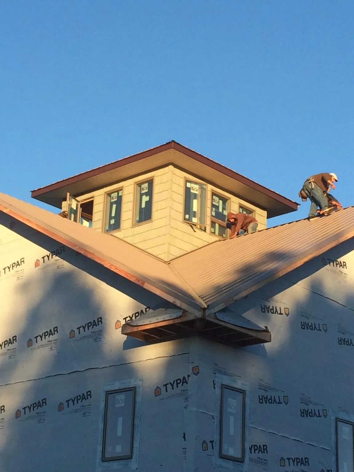 Roofers working around a rooftop cupola on a new metal roof at sunset — Roof Waterproofing in Ashley by Roofing Brothers